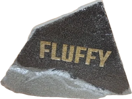 A dark speckled stone with the name Fluffy in gold-filled lettering.